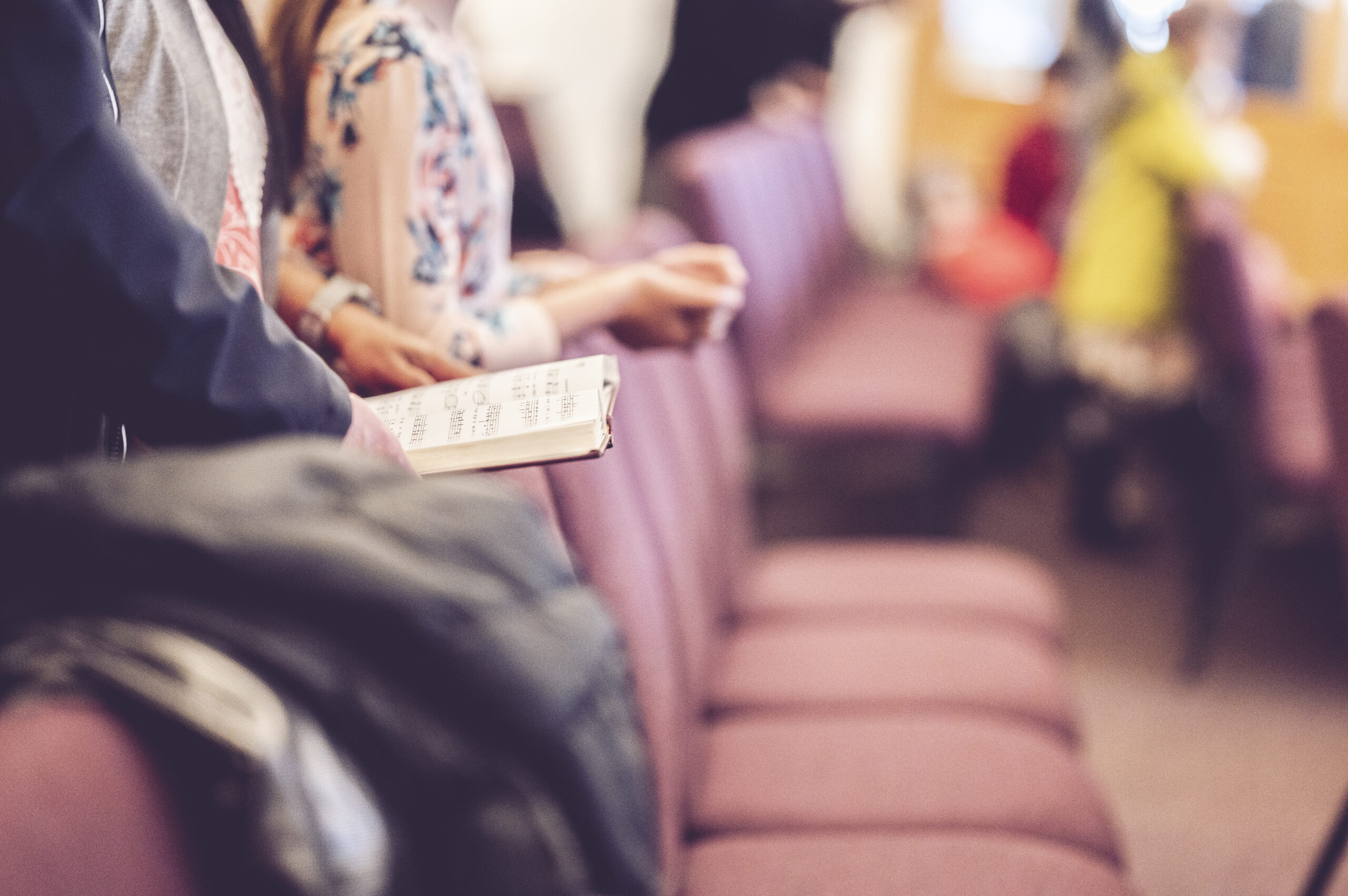 Selective focus shot of a man in long sleeves holding a songbook in the church